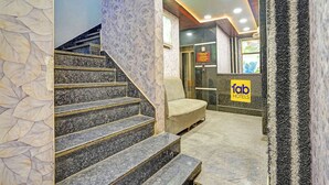 A hotel lobby with a marble staircase, a reception desk, and a check-in/out sign. - Fabhotel Vishal Residency (Varanasi)