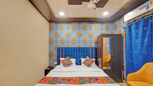 A bedroom with a bed, a ceiling fan, a wardrobe, and a chair. - Fabhotel Vishal Residency (Varanasi)