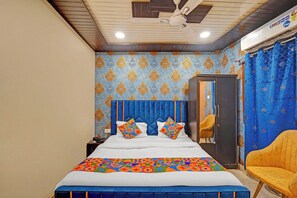 A bedroom with a bed, a ceiling fan, a wardrobe, and a chair. - Fabhotel Vishal Residency (Varanasi)
