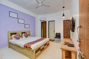 A bedroom with a bed, a desk, a chair, a ceiling fan, and a TV mounted on the wall. - Fabhotel Imperial Inn (Paud)