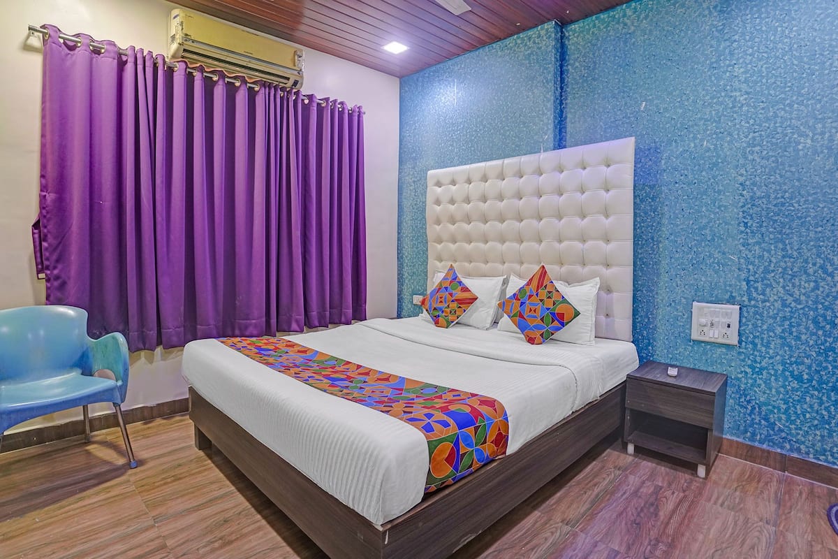 Un dormitorio con una cama grande, cortinas moradas, una silla azul y una pared azul con textura.