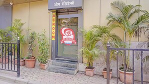A hotel entrance with a sign in Hindi, a red logo with an Om symbol, and potted plants around the entrance. - Fabhotel Om Residency (Mumbai)