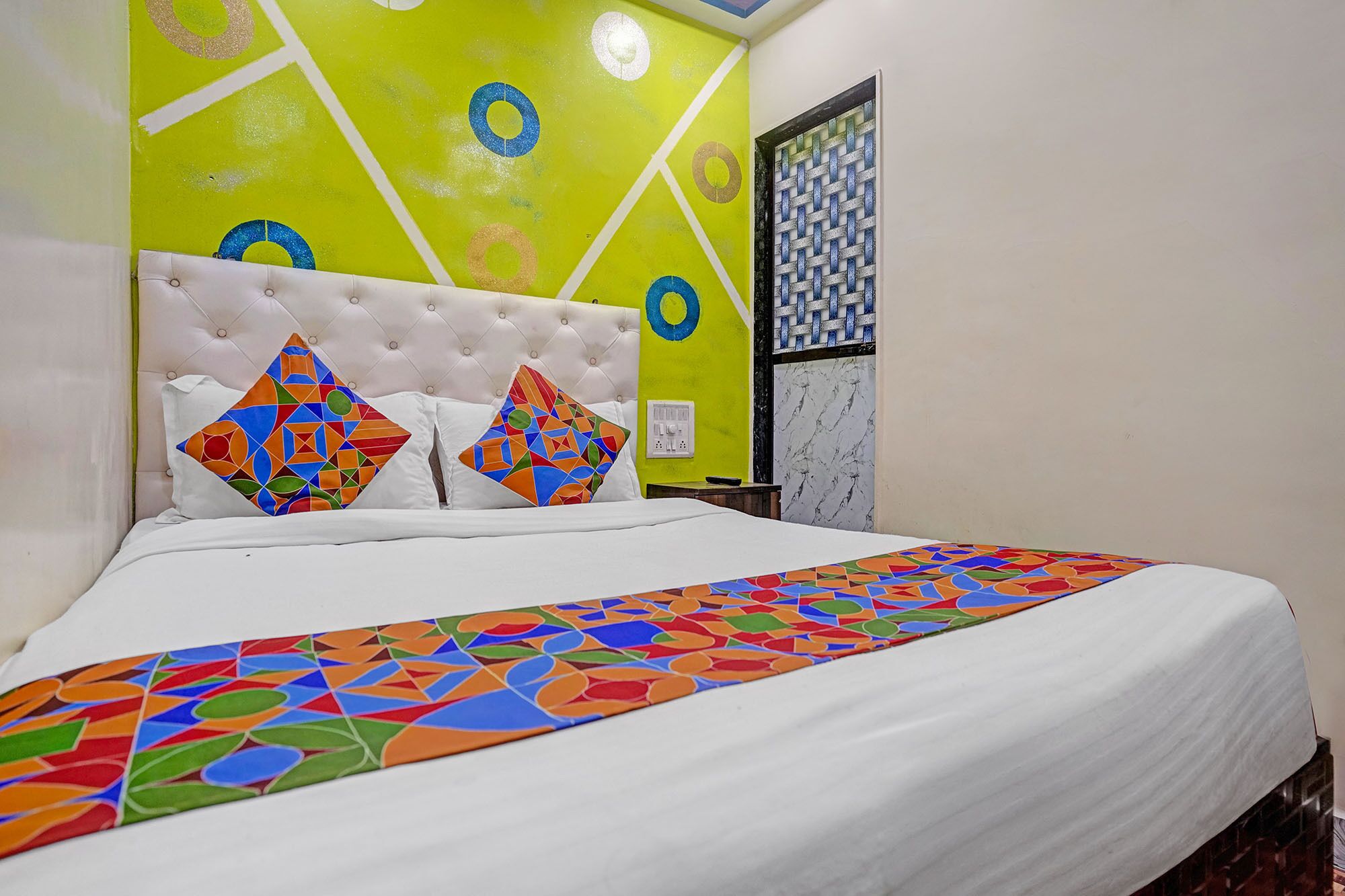 A bed with a white headboard and colorful geometric-patterned pillows.
