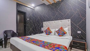 A bedroom with a bed, a chair, and a nightstand. - Fabhotel Om Residency (Mumbai)