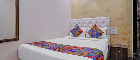 A hotel room with a bed, a nightstand, a mirror, and a textured wall.