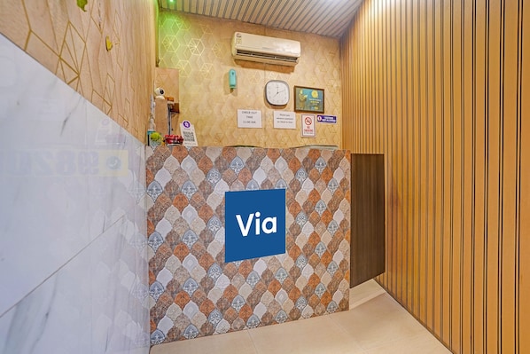 A hallway with a patterned wall, a clock, a 'Check Out' sign, and a 'Via' sign. - Fabhotel Om Residency (Mumbai)