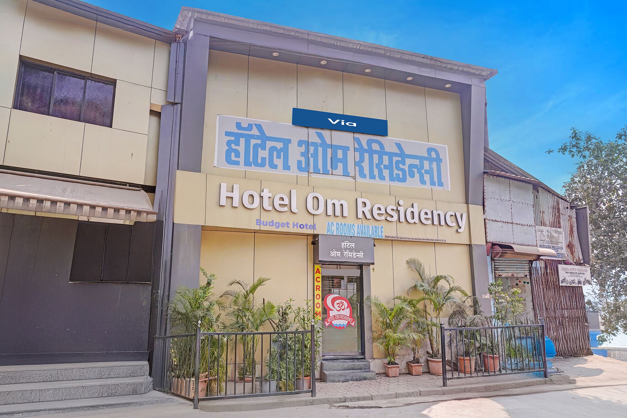 Un edificio con un letrero que indica 'Hotel Om Residency' y 'Hotel Económico', mostrando que hay habitaciones con aire acondicionado.