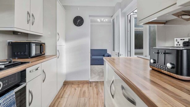 A modern kitchen with white cabinets, a microwave, a toaster, and a clock on the wall. - East Croydon Home, Near Station & Gatwick Airport (Greater London)