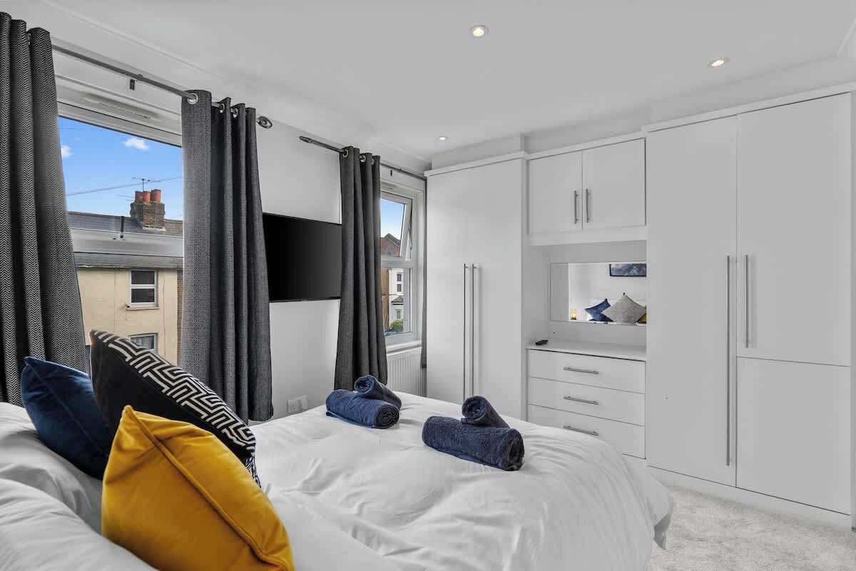 Ein modernes Hotelzimmer mit einem großen Bett, einem weißen Kleiderschrank und einem an der Wand befestigten Fernseher.