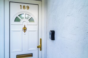 Une porte blanche portant le numéro 189, une poignée de porte en laiton et un sonnette.