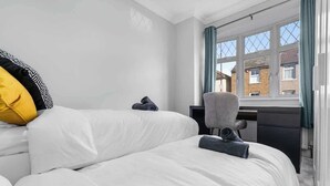 A bedroom with two beds, a desk, and a window with curtains. - East Croydon Home, Near Station & Gatwick Airport (Greater London)