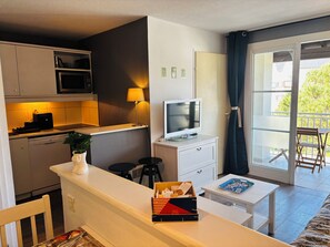 A modern room with a kitchen, a dining area, a TV, and a balcony with a view. - Apartment Arzon - 1 bedroom and terrace (Arzon)