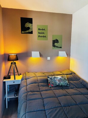A bedroom with a bed, a desk with a lamp, and motivational posters on the wall. - Apartment Arzon - 1 bedroom and terrace (Arzon)