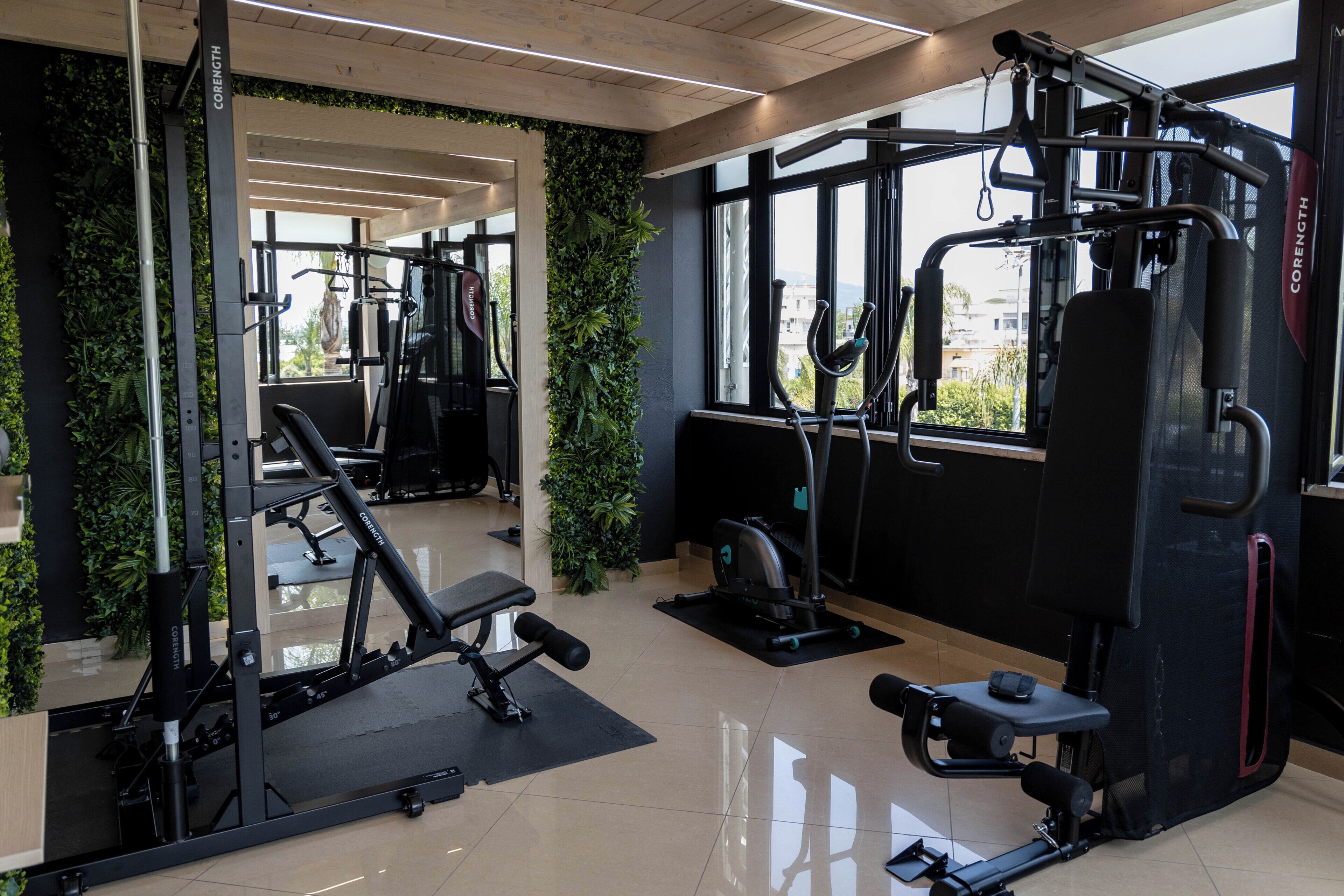 A gym with exercise equipment, a bench, and a wall-mounted plant.