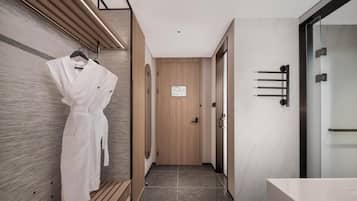 A modern hotel hallway with a wooden bench, a robe hanging on the wall, and a door with a sign.