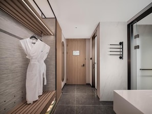 Un pasillo moderno de hotel con un banco de madera, una bata colgada en la pared y una puerta con un letrero.