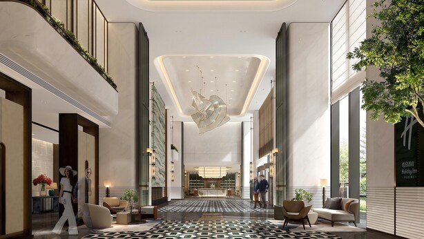 Eine großzügige Lobby mit einem geometrischen Deckenmuster, einer zentralen Rezeption und einem gemusterten Boden.
