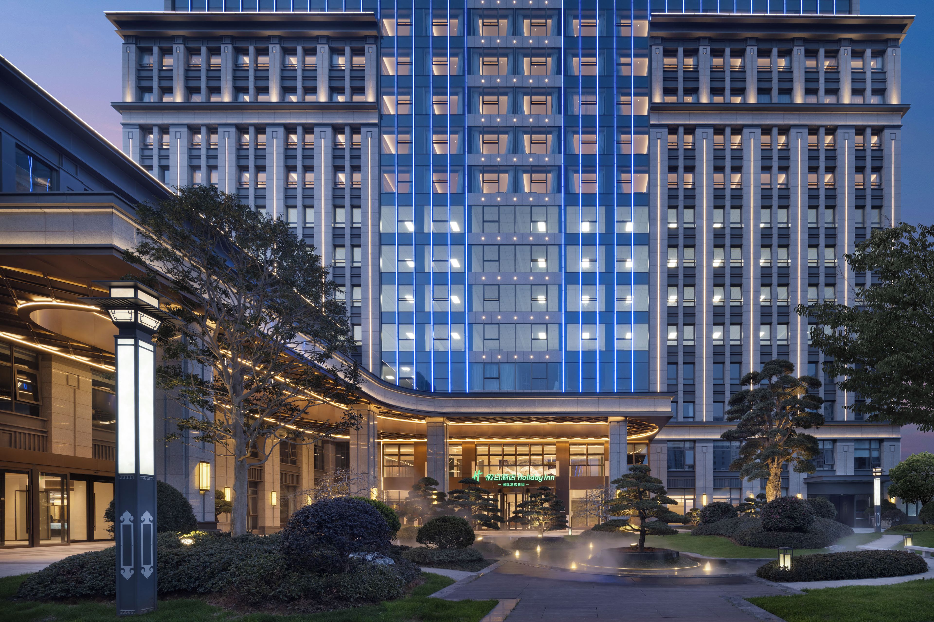 A multi-story hotel with a modern facade, large windows, and a well-lit entrance.