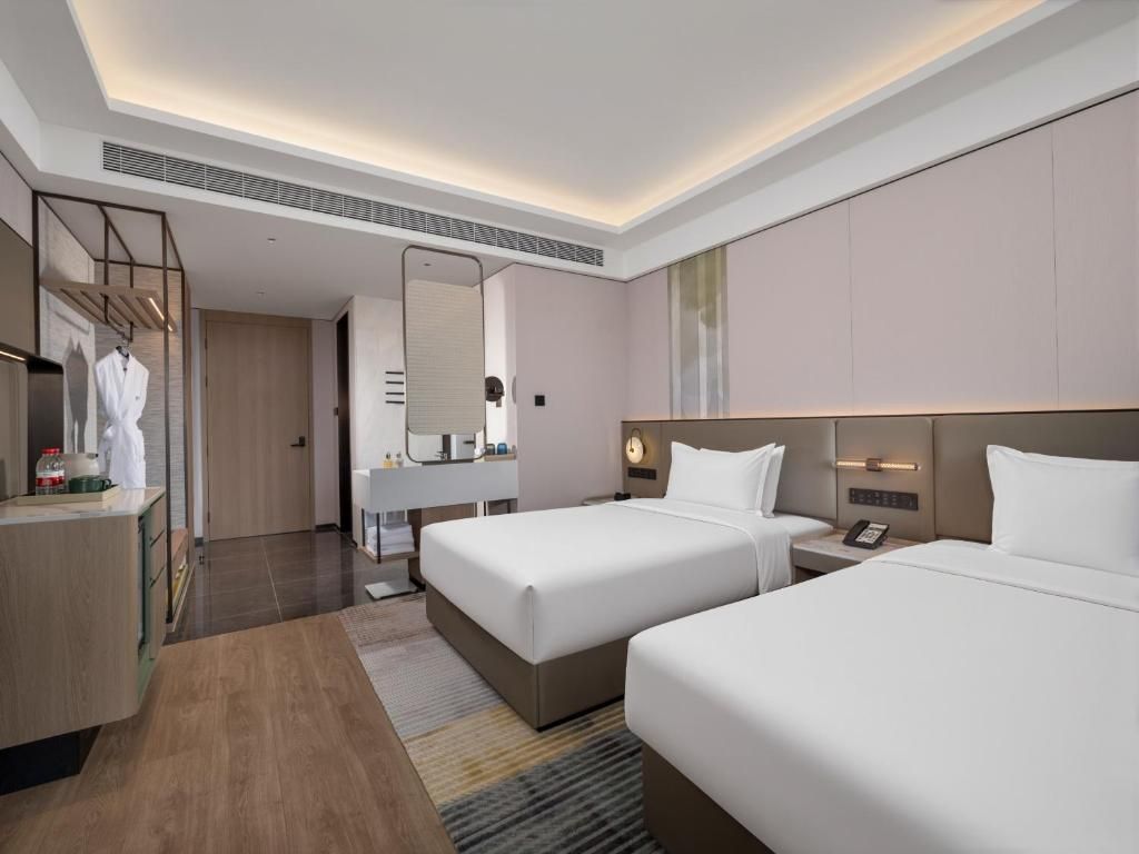 Habitación de hotel con dos camas, baño, tocador y espejo.
