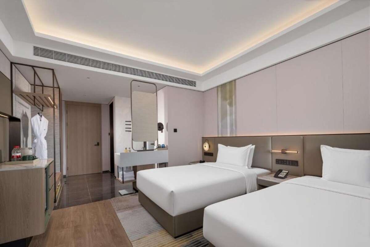 A hotel room with two beds, a bathroom, a vanity, and a mirror.