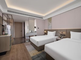 Habitación de hotel con dos camas, baño, tocador y espejo.