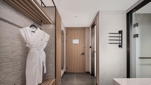 Ein moderner Hotelkorridor mit einer Holzbank, einem an der Wand hängenden Bademantel und einer Tür mit einem Schild.