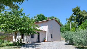 Une maison à deux étages, avec un toit en tuiles, un mur en pierre et une cour dallée.