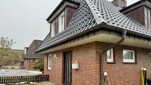 Una casa residenziale con facciata in mattoni, tetto spiovente e un piccolo portico.