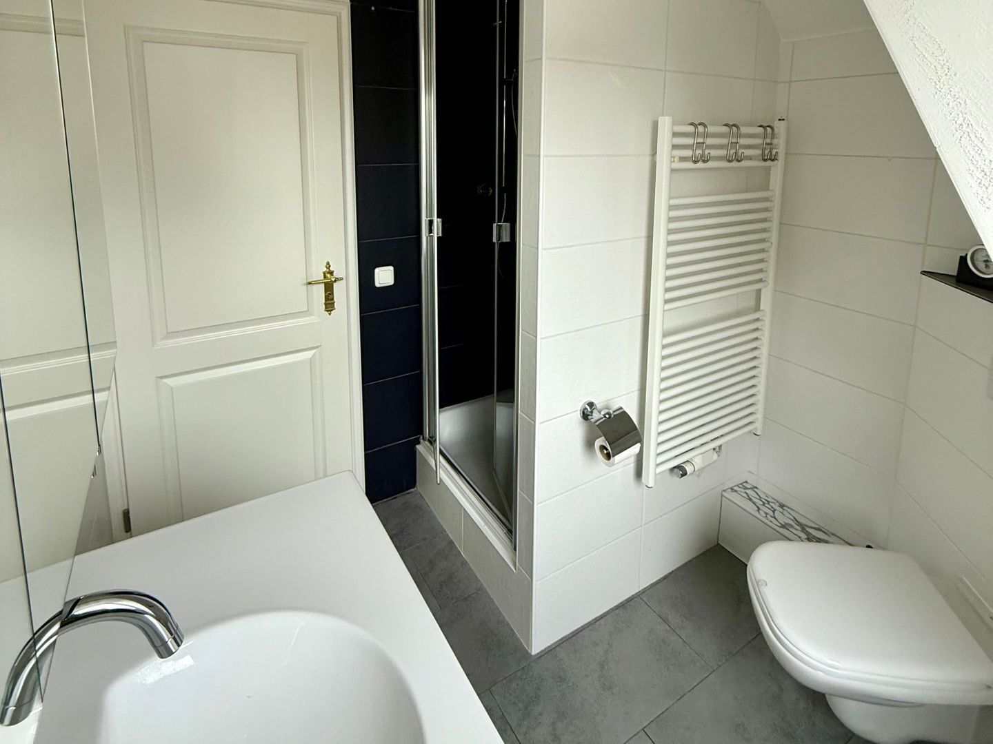 A bathroom with a white bathtub, a toilet, and a shower area.