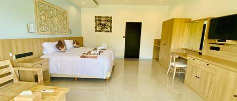 Una habitación de hotel moderna con una cama grande, un escritorio, una silla, un televisor y un ventilador de techo.