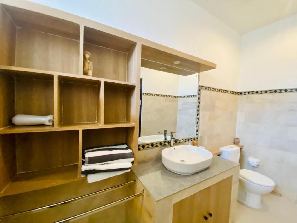 A bathroom with a wooden vanity, a sink, and a toilet.