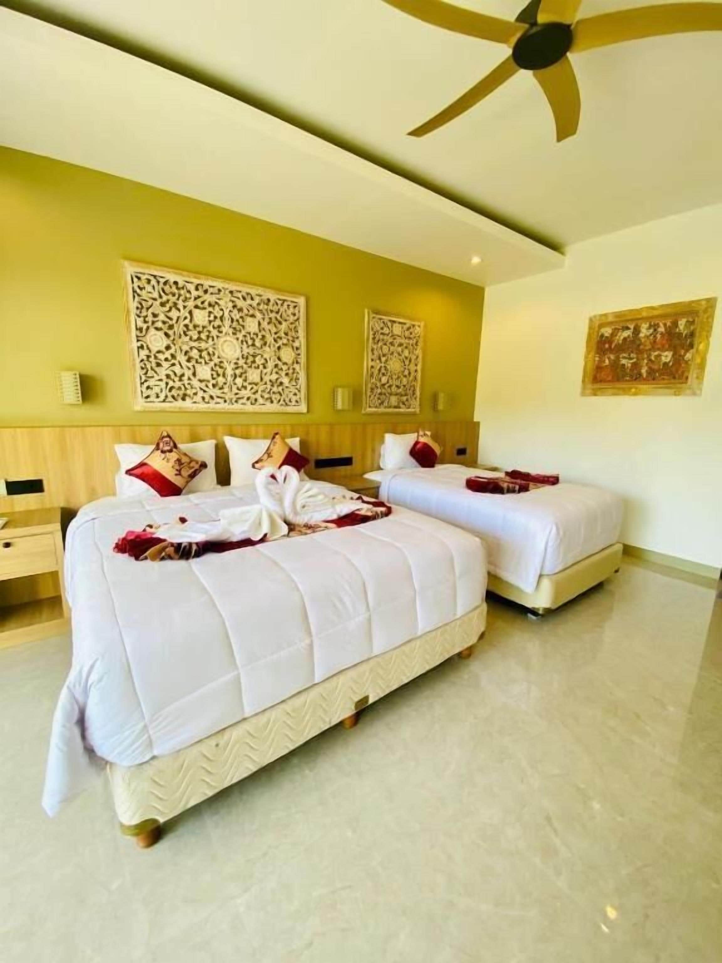 A hotel room with two beds, a ceiling fan, and decorative wall art.