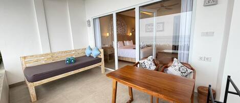 A room with a wooden bench, a wooden table, and a bed with white bedding.