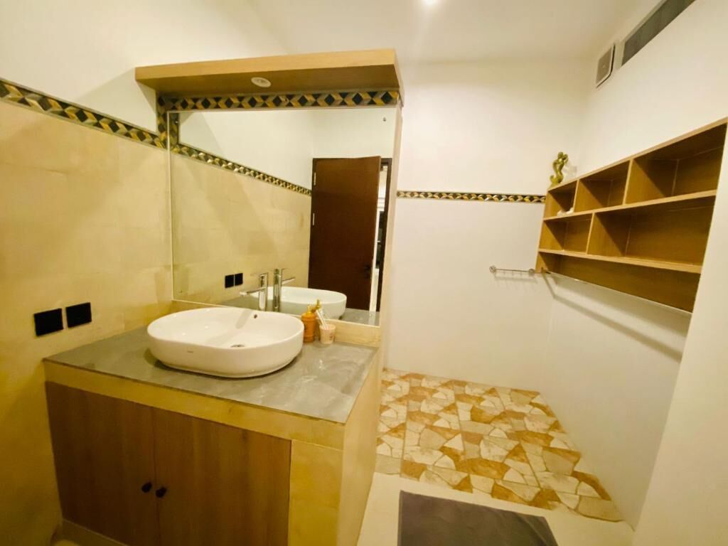A bathroom with a sink, mirror, and shelves.