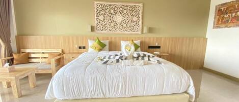 A hotel room with a large bed, a wooden headboard, a decorative wall piece, and a small table with a chair.
