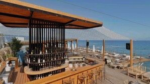 A wooden deck bar with a view of the sea, outdoor seating, and umbrellas. - Hotel Porta Ksamil (Ksamil)