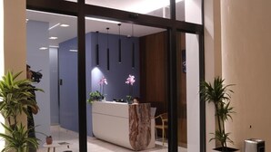 A reception area with a marble counter, potted plants, and hanging pendant lights. - Hotel Porta Ksamil (Ksamil)