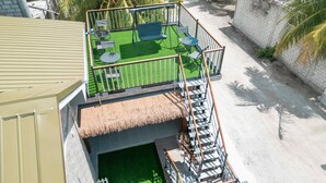 Una terraza en la azotea con techo de paja, una piscina pequeña y mobiliario de exterior.