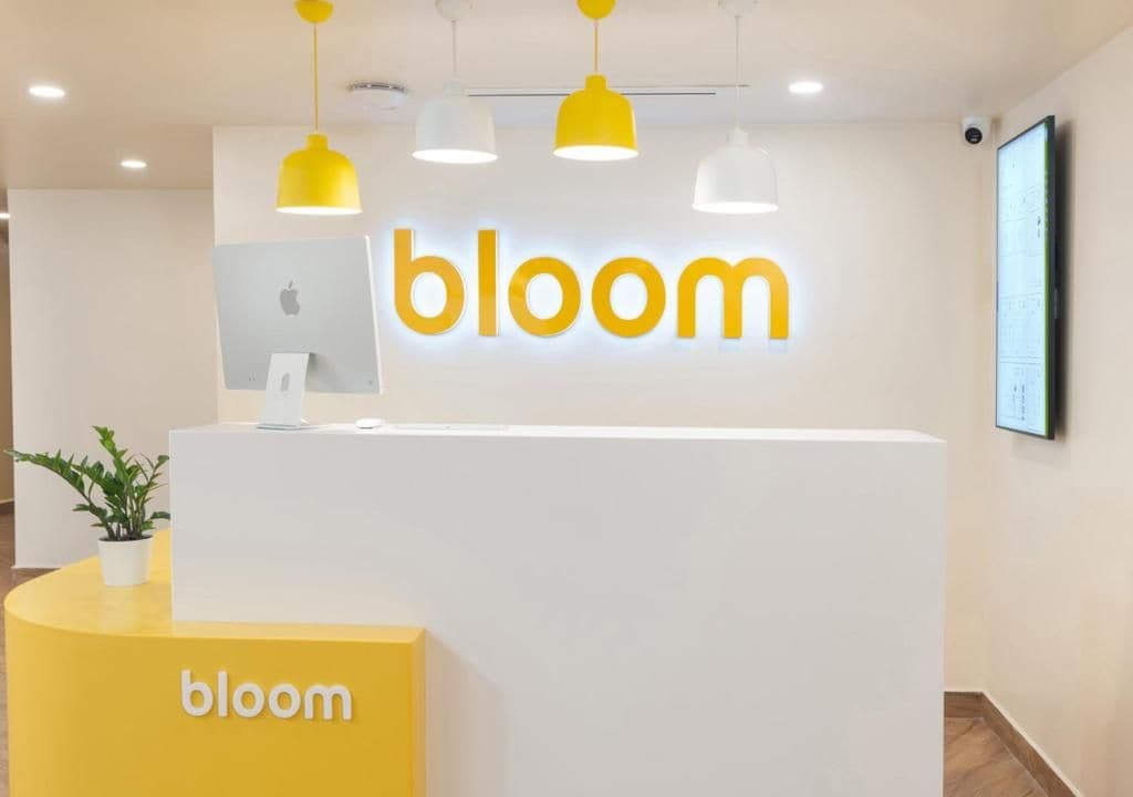 A reception desk with the word 'bloom' prominently displayed above it.