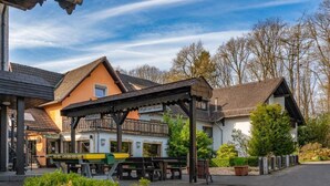 Un bâtiment de style chalet traditionnel, doté d’un balcon, d’un espace extérieur couvert aménagé en coin salon et offrant une vue sur un ciel dégagé.
