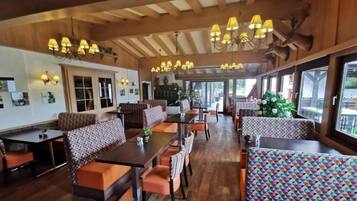Een restaurant met houten balken, patroonstoelen en hangende kroonluchters.