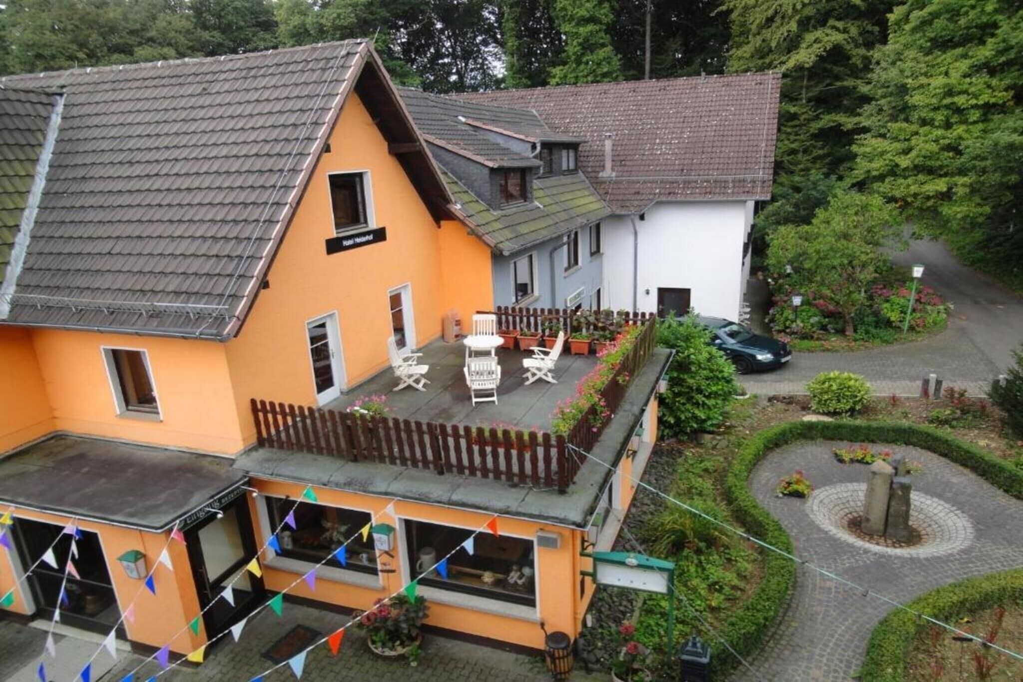 Un bâtiment à deux étages, doté d’un toit en pente, d’un balcon avec des sièges extérieurs et d’une allée pavée.