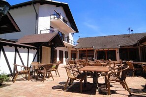 Eine Terrasse im Freien mit Korbmöbeln und einem Gebäude mit einem Ziegeldach.