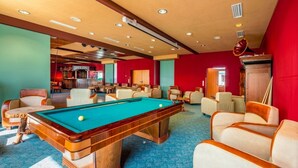 Une table de billard dans une pièce dotée de plusieurs espaces de détente et d’un bar.