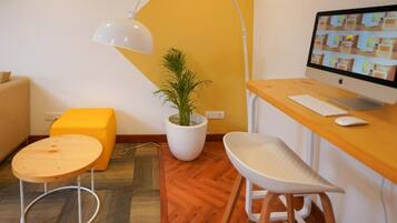 A modern office space with a desk, computer, chair, lamp, and a potted plant.