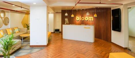 A modern reception area with a herringbone floor, a reception desk, and a seating area with a sofa and a yellow armchair.