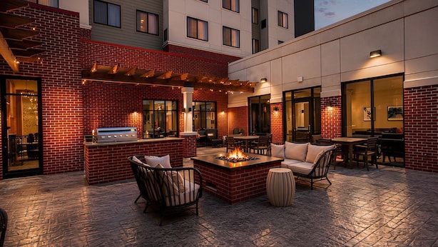 A rooftop patio with outdoor seating, a fire pit, and a bar area.