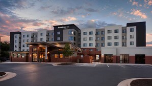 A multi-story hotel with a modern design, featuring a prominent entrance with a covered walkway and a large sign.