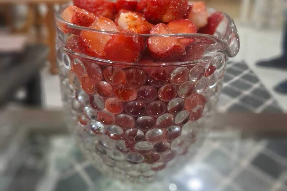 A glass with tapioca pearls and strawberries on a table.