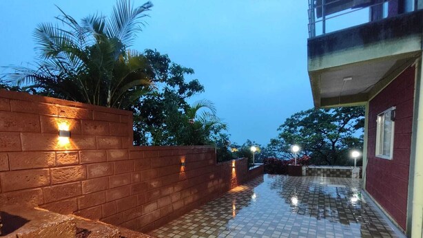 A tiled outdoor area with brick walls and a red building. - Red Soil Strawberry Farm villa (Bhuteghar)